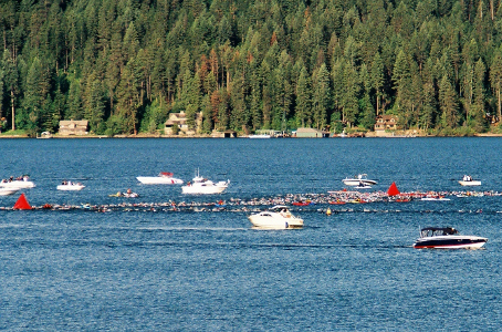 [This is quite a ways into the lake so the swimmers are more of a thin line along the route as the faster ones have pulled ahead. There are more than a half-dozen boats at points along the route.]